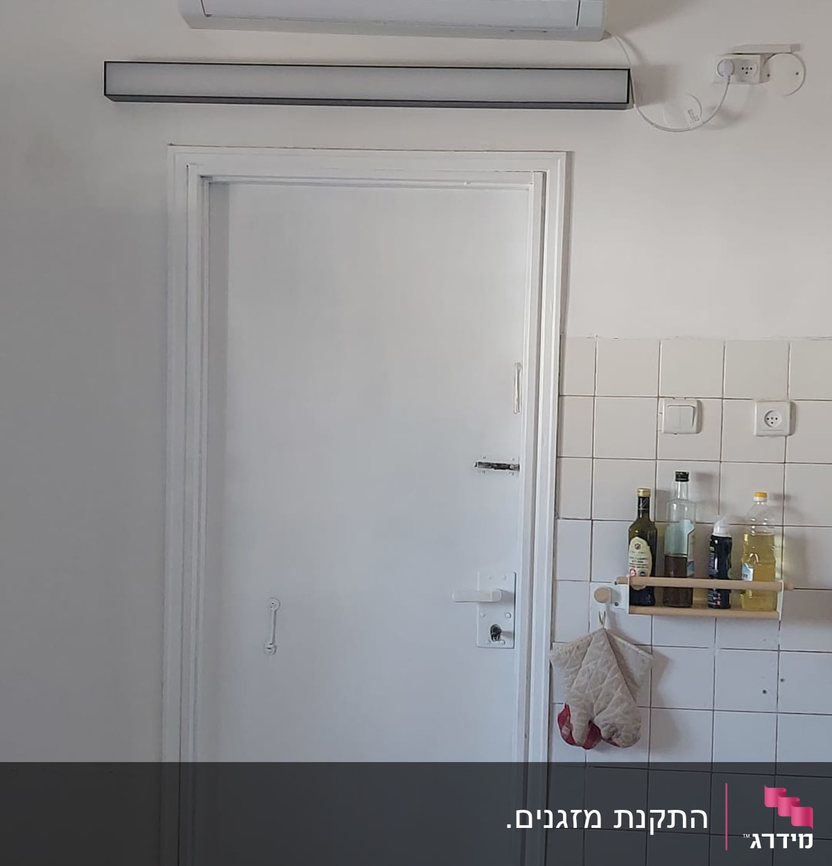 מזגן מותקן על קיר מעל דלת לבנה